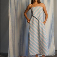 Woman wearing a strapless dress with vertical stripes in front of a striped curtain.